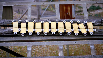 Exposure, still: Line on yellow plates: This shot is one of a number in the film where I mixed scratching marks made directly on to unprocessed celluloid and scanned on to my PC, with stills images of the site. In this case the scratch was a longish wavy line, scanned in reverse (dark scratch on light background) &amp; laid over images of the line on the series of yellow plates. The next step was to rub out, on PC using a software package called AURA, the points where the scratches extended beyond the plates.